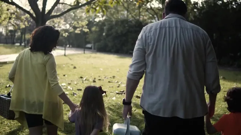 Familia de espaldas caminando de la mano en un parque. Escena ilustrativa de bienestar.